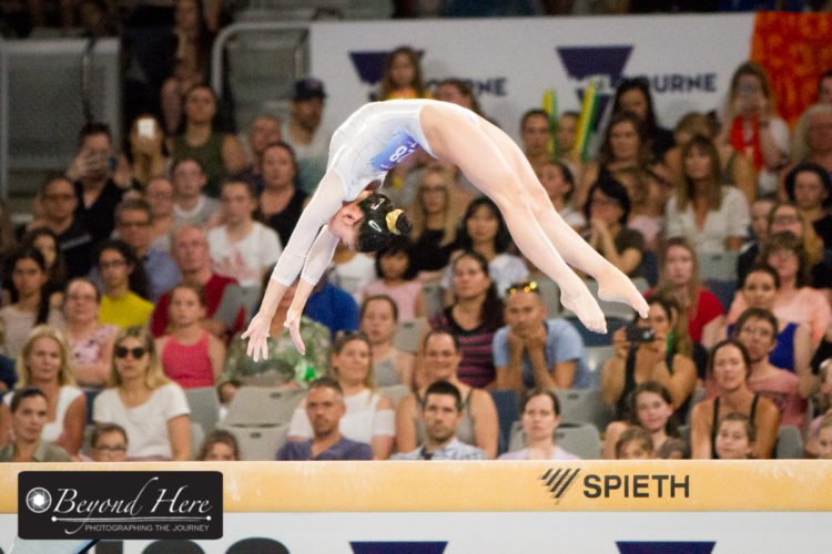 Gymnast doing back flip on beam