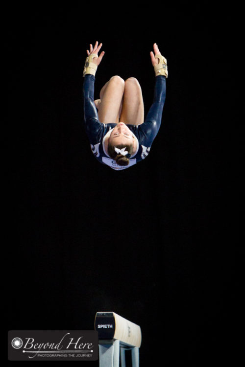 Gymnast in mid air above the beam